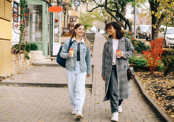 two-happy-carefree-multiracial-girlfriends-walking-city-street-with-take